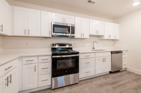 A modern kitchen with white cabinets and stainless steel appliances.